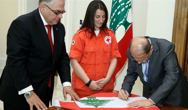 بالصورة: عون وقّع على علم ستغرسه مسعفة في الصليب الاحمر على جبال هملايا