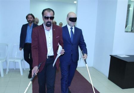 حاصباني معصّب العينين وممسكًا بالعصا البيضاء